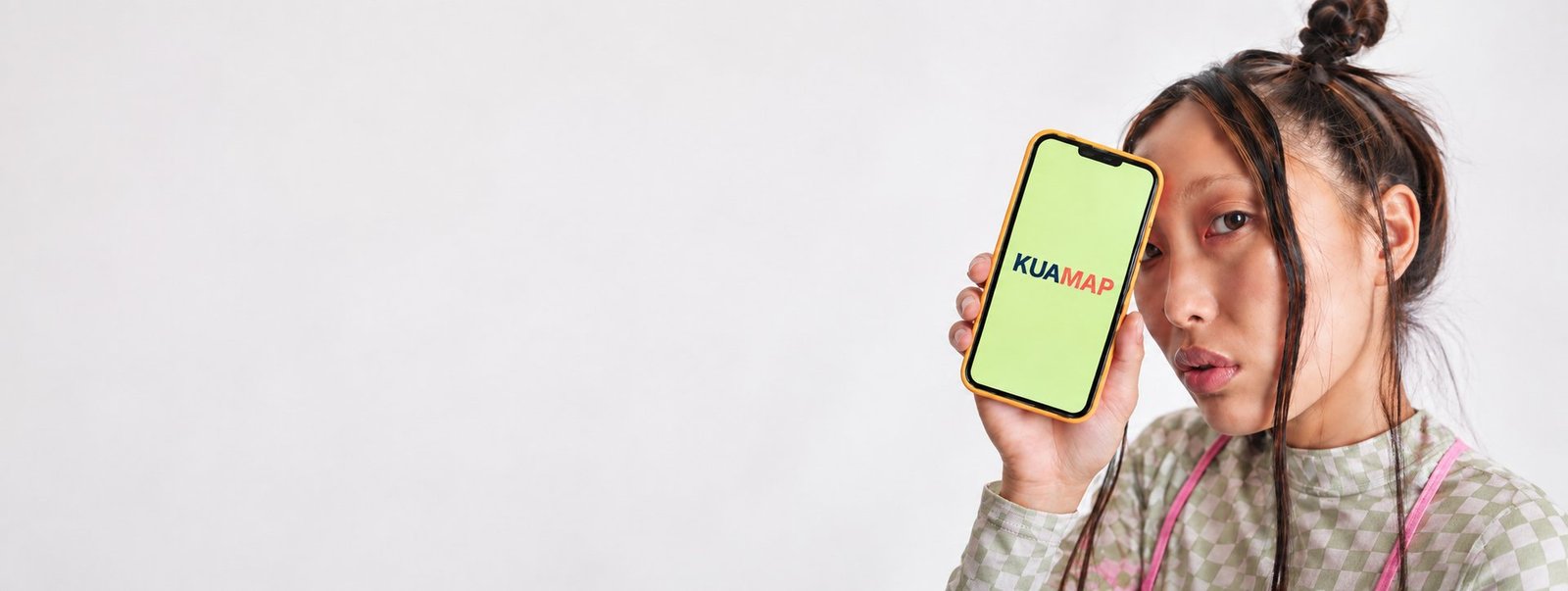 Una joven sostiene un m&oacute;vil que muestra la marca Kuamap
